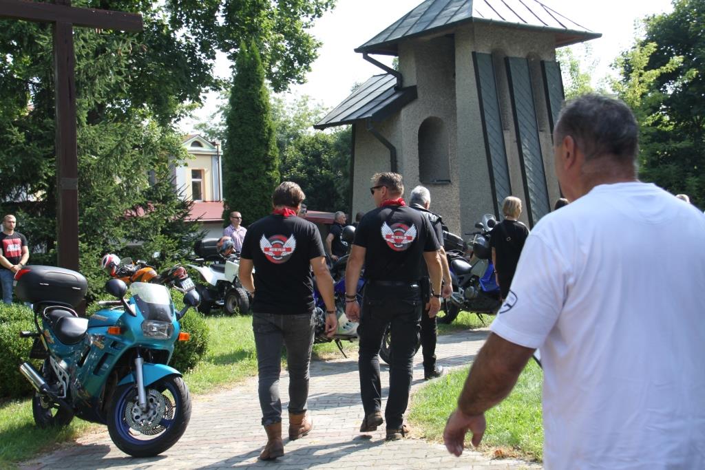 Grupa motocyklistów - widok od tyłu na logo na koszulach, dookoła stoją motocykle