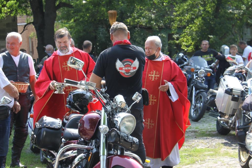  Enlarge Image 	Ksiądz w czerwonej sutannie dokonuje poświęcenia motocykli stojących na dworze 