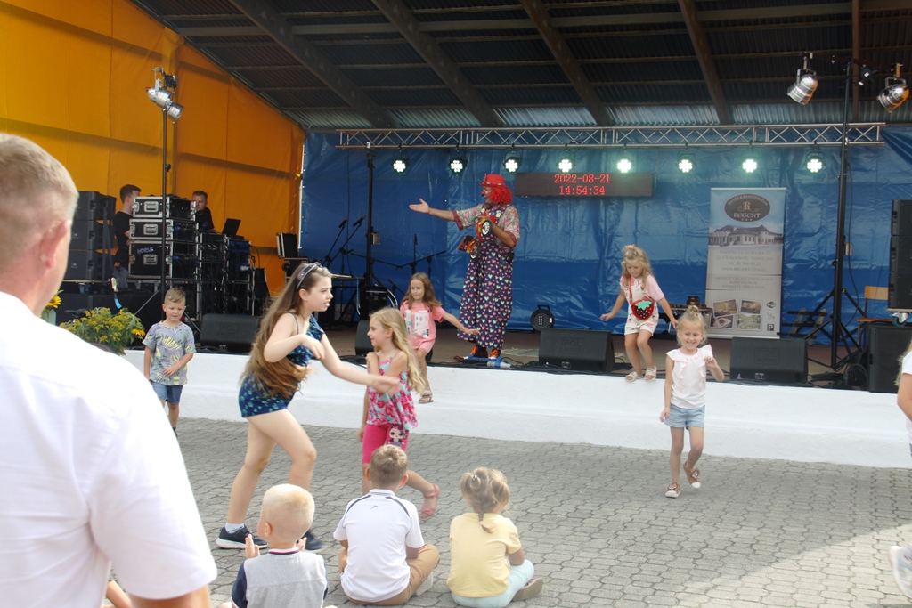 Biegające dzieci przed sceną, na scenie klaun